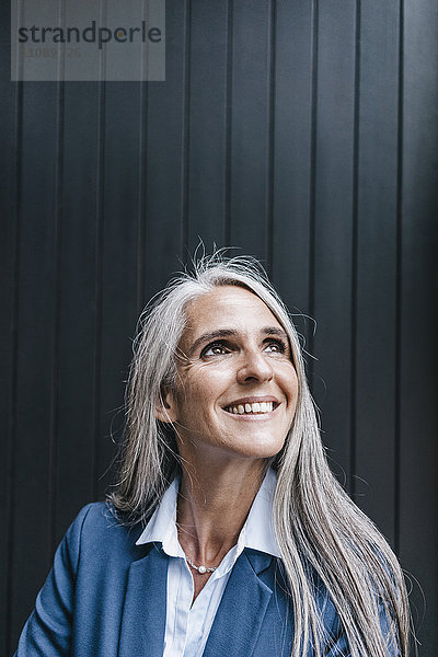 Porträt einer lächelnden Frau mit langen grauen Haaren nach oben schauend