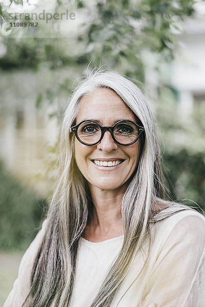 Porträt einer lächelnden Frau mit langen grauen Haaren und Brille