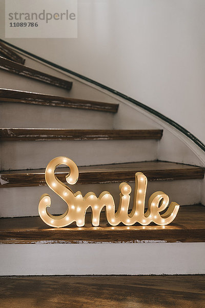 Leuchtendes Wort'Lächeln' auf Holzstufen