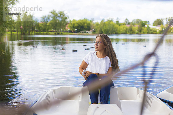 Russland  Tichwin  Teenagermädchen mit Smartphone  im Boot sitzend