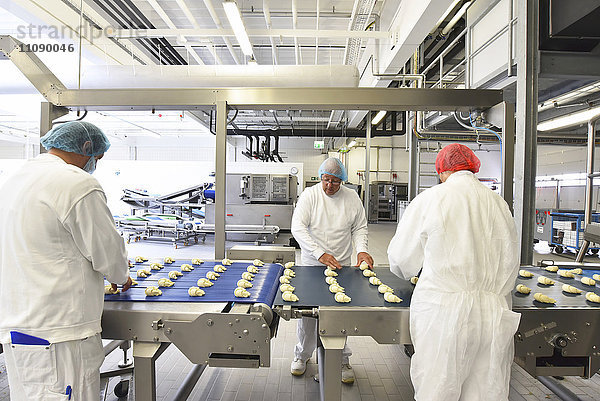 Arbeiter an der Produktionslinie einer Backfabrik mit Croissants