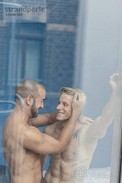 Schwules Paar umarmt am Fenster