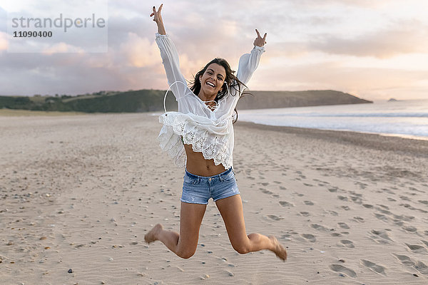 Spanien  Asturien  schöne junge Frau beim Springen am Strand