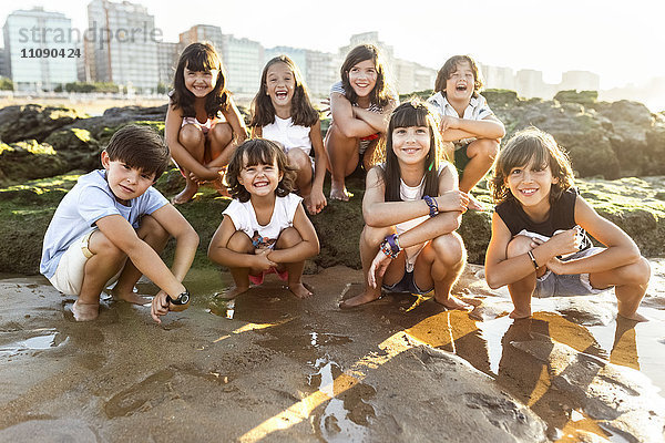 Gruppe glücklicher Kinder am Strand bei Sonnenuntergang