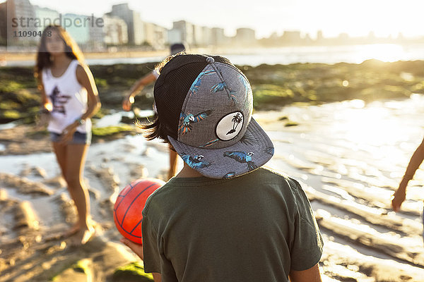 Kinder spielen mit einem Ball am Strand bei Sonnenuntergang