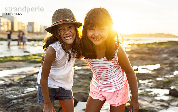 Portrait von zwei lächelnden Mädchen am Strand bei Sonnenuntergang