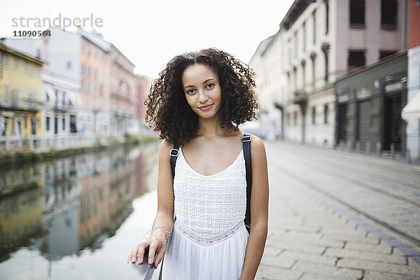 Italien  Mailand  Porträt einer lächelnden jungen Frau mit lockigem braunem Haar