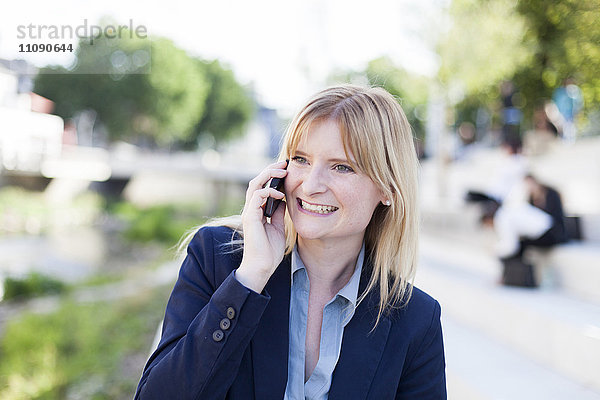 Porträt einer lächelnden blonden Geschäftsfrau am Telefon