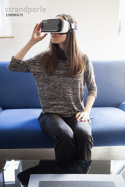 Frau auf der Couch sitzend mit Virtual-Reality-Brille