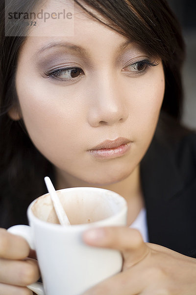Junge Frau mit einer Tasse Kaffee  die sich etwas ansieht.
