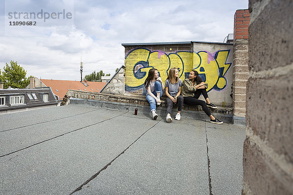 Drei Teenager-Mädchen sitzen zusammen auf dem Dach.