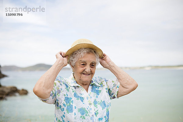 Porträt einer lächelnden Seniorin mit Strohhut