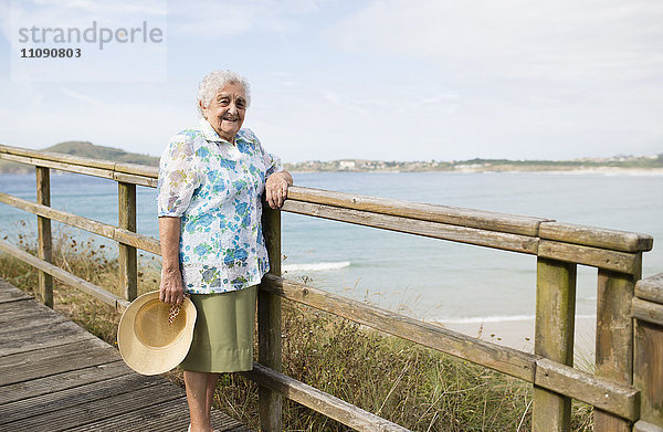 Fröhliche Seniorin an der Strandpromenade stehend