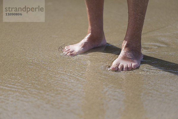 Füße der älteren Frau am Strand