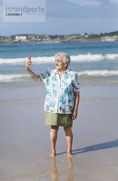 Seniorenfrau  die sich selbst am Strand mitnimmt.