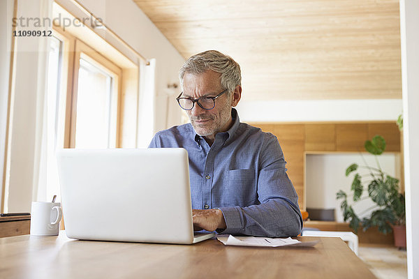 Erwachsener Mann mit Laptop auf dem Tisch zu Hause