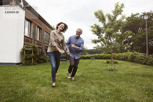 Ein glückliches reifes Paar  das im Garten läuft