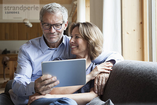 Ein reifes Paar teilt sich ein digitales Tablett auf der Couch.