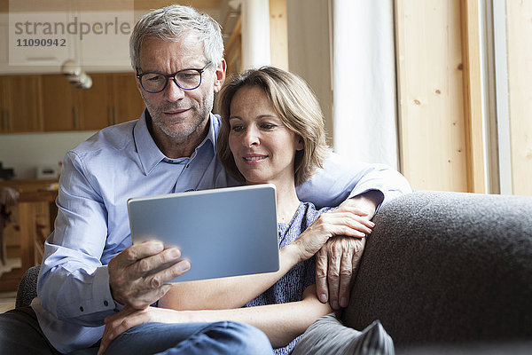 Ein reifes Paar teilt sich ein digitales Tablett auf der Couch.
