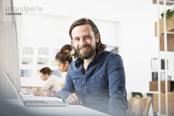 Lächelnder Mann im Büro mit Laptop