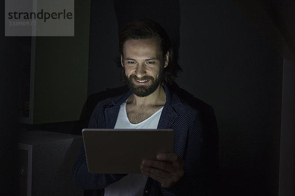 Mann mit digitalem Tablett im Dunkeln