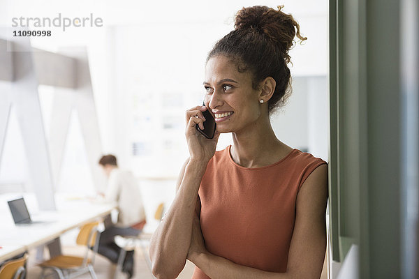 Lächelnde Frau im Büro auf dem Handy