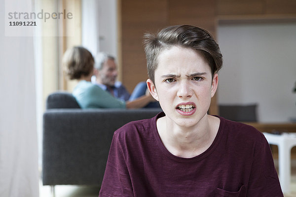 Porträt des wütenden Teenagers zu Hause mit Eltern im Hintergrund