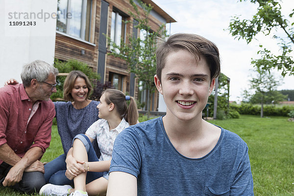 Porträt eines lächelnden Teenagers mit seiner Familie im Garten