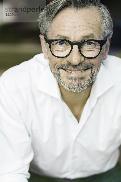 Porträt eines lächelnden Mannes mit grauen Haaren und Bart mit Brille