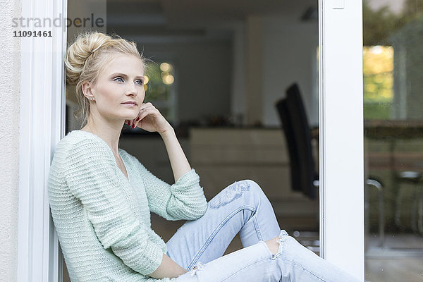 Blonde Frau an der Terrassentür sitzend