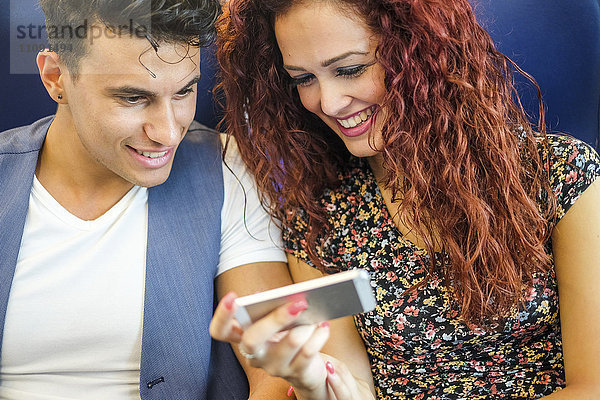 Lächelndes junges Paar beim Blick aufs Handy