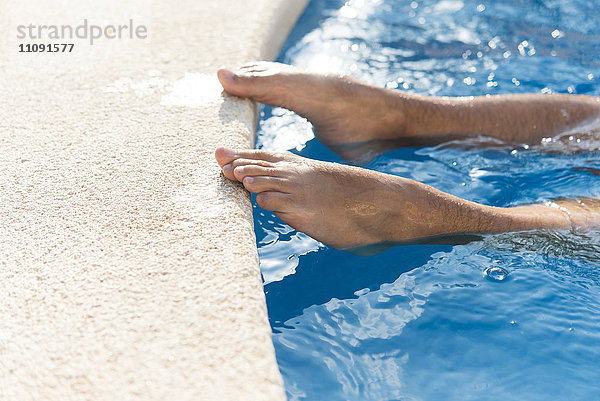 Nackte Füße des Mannes am Rande des Swimmingpools
