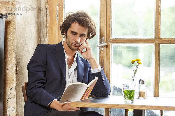 Junger Mann im Café beim Lesen eines Buches