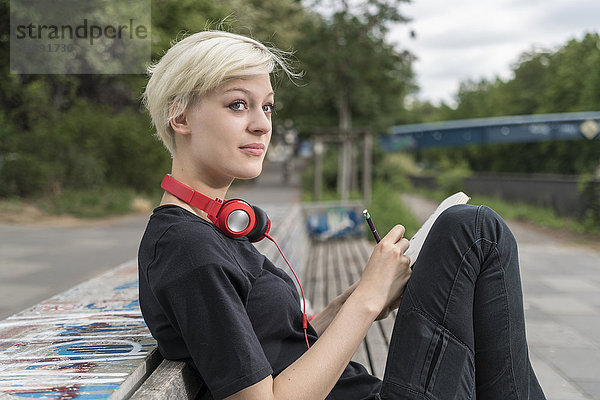 Junge Frau mit Kopfhörerzeichnung auf Parkbank