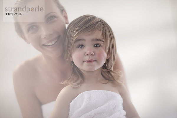 Lächelnde junge Frau und kleines Mädchen in ein Handtuch gewickelt