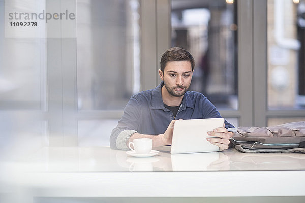 Mann mit digitalem Tablett am Schreibtisch