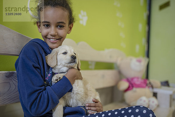 Mädchen mit Labrador-Welpe beim Tierarzt