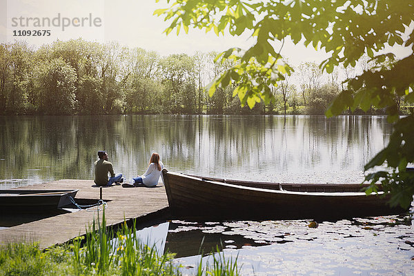 Pärchen entspannen sich am sonnigen Seeufer in der Nähe des Kanus