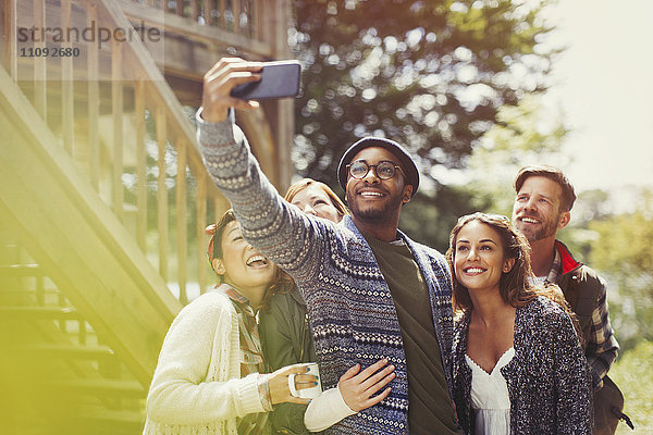 Lächelnde Freunde mit Fotohandy  die Selfie nach draußen bringen.