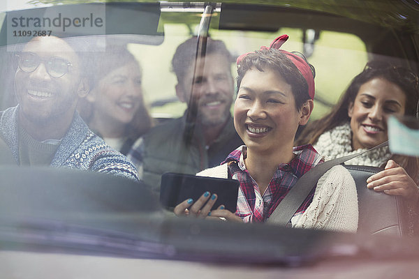 Lächelnde Freunde mit GPS auf dem Smartphone beim Autofahren