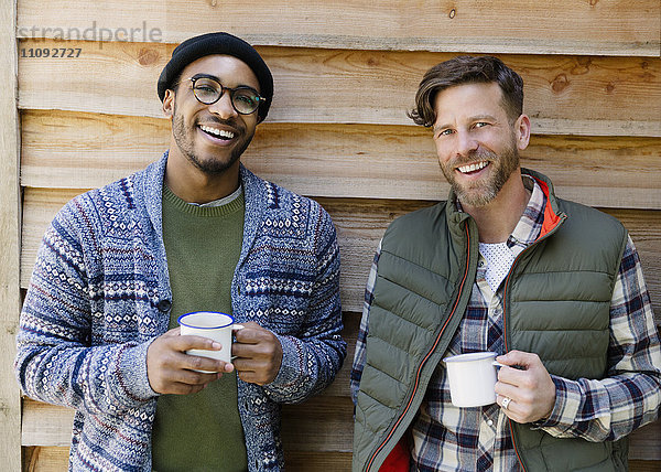 Portrait lächelnde Männer beim Kaffeetrinken außerhalb der Kabine