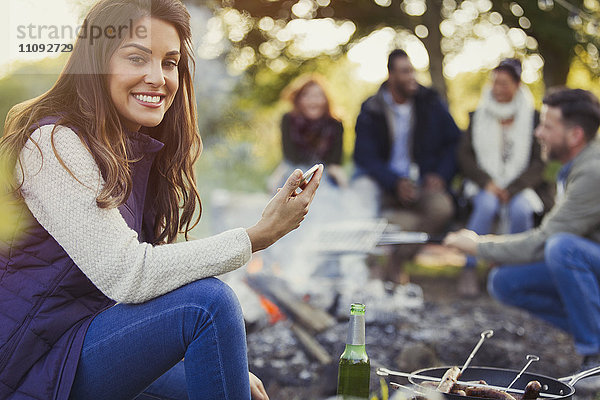 Portrait lächelnde Frau beim SMSen und Biertrinken auf dem Campingplatz