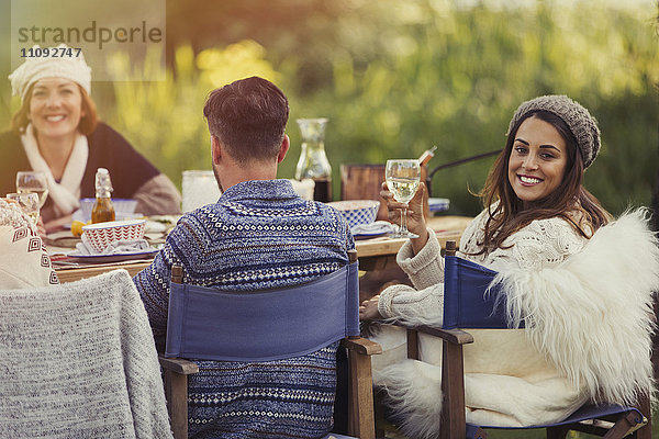 Portrait lächelnde Frau beim Weintrinken am Gartentisch