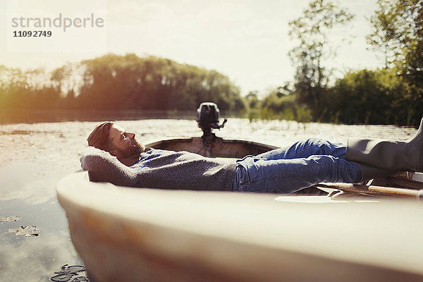 Ruhiger Mann  der im Kanu auf dem sonnigen See liegt.