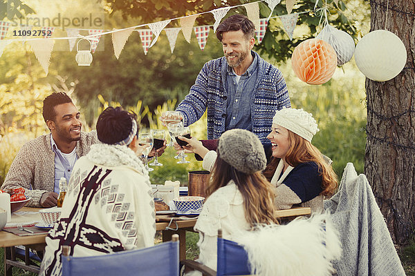 Freunde rösten Weingläser am Garten-Lunch-Tisch