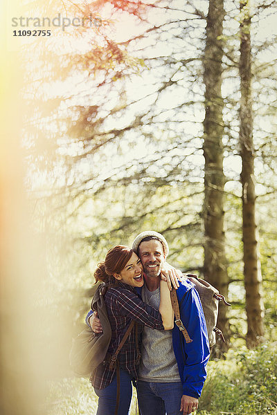 Porträt eines begeisterten Paares mit Rucksackwandern in sonnigen Wäldern