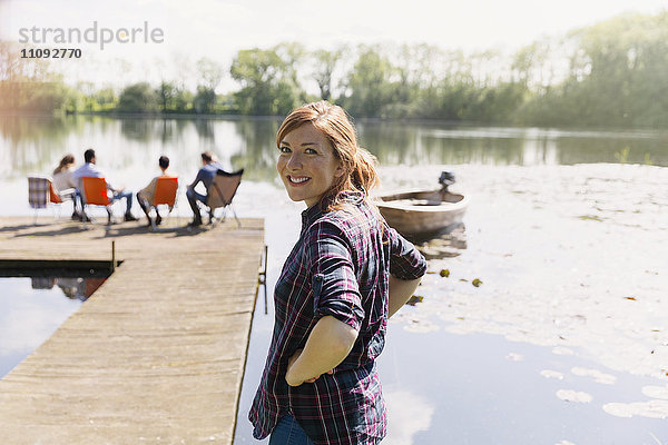 Porträt einer lächelnden Frau am sonnigen Ufer des Sees