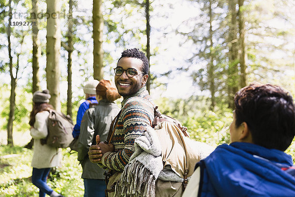 Portrait lächelnder Mann mit Rucksackwanderung in sonnigen Wäldern