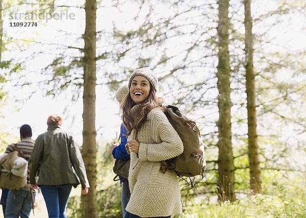 Enthusiastische Frau mit Rucksackwandern in sonnigen Wäldern