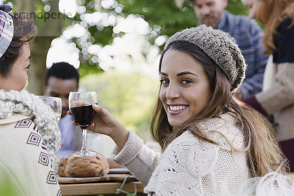 Portrait lächelnde Frau beim Weintrinken auf der Terrasse mit Freunden